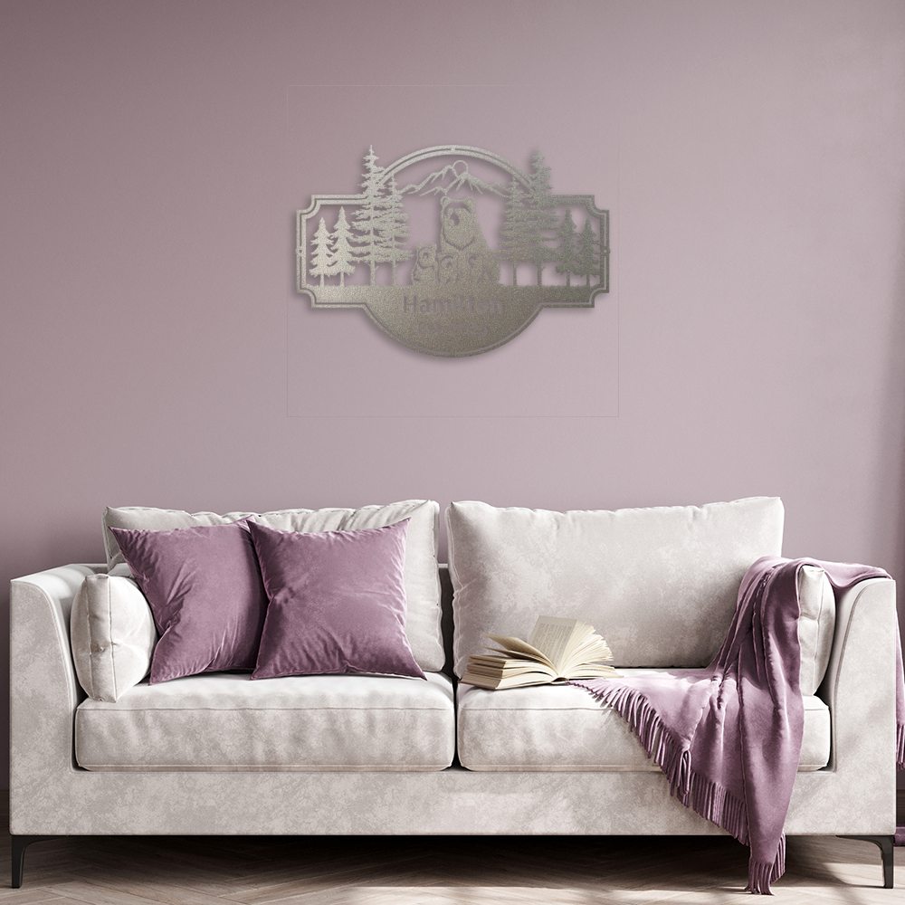 Personalized Bear Family Metal Sign – Custom Cabin & Family Name Wall Art in silver against a light purple wall hanging above an off-white sofa with an open book, purple throw, and pillows.