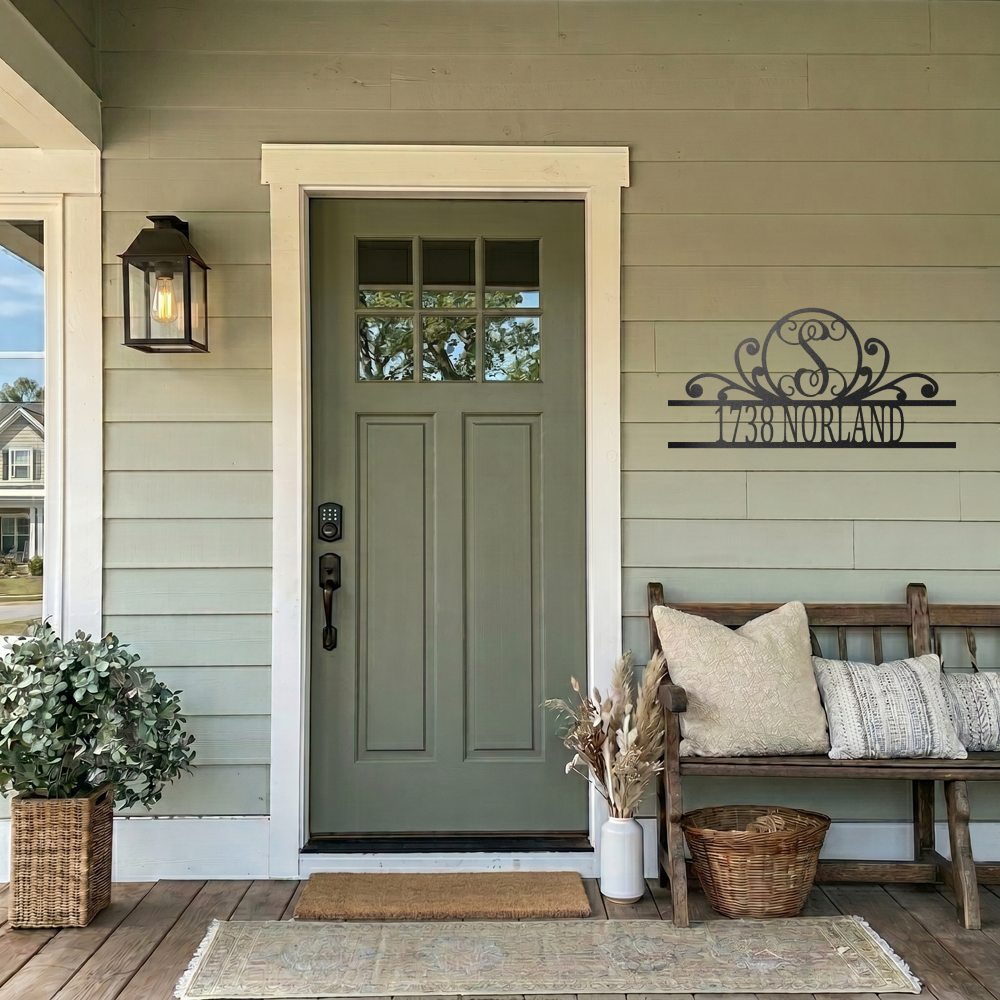 Personalized scroll monogram metal address sign with house number and street name displayed beside a front door